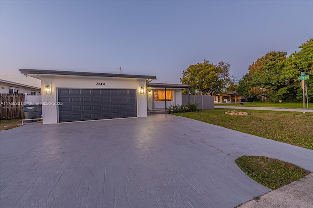 view of front of house featuring a yard, driveway, an attached garage, and stucco siding