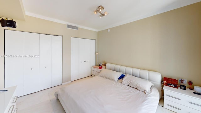 bedroom with multiple closets, visible vents, and crown molding