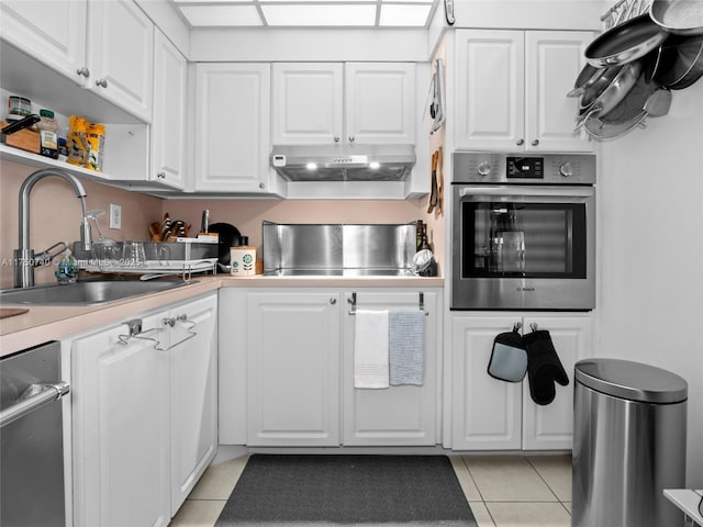 kitchen featuring under cabinet range hood, appliances with stainless steel finishes, white cabinets, and a sink