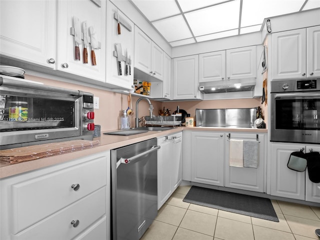 kitchen with light tile patterned floors, white cabinets, appliances with stainless steel finishes, light countertops, and under cabinet range hood