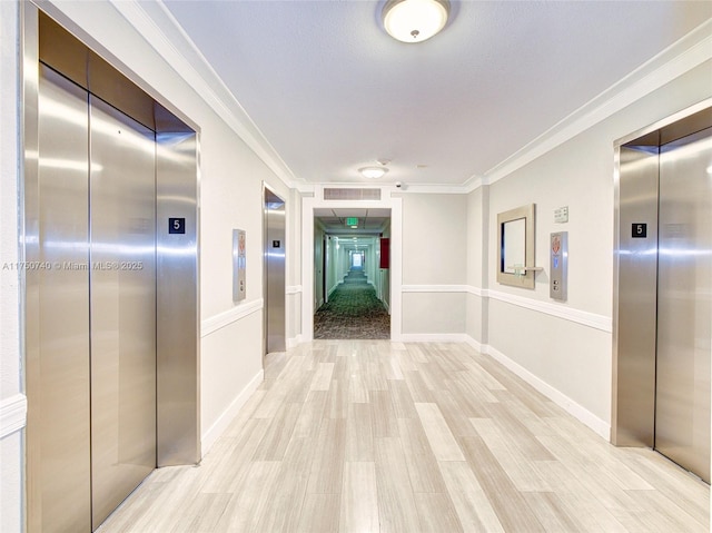 hall featuring ornamental molding, elevator, and light wood finished floors