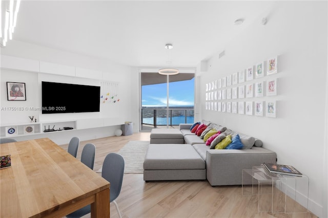 living area with a wall of windows, visible vents, and light wood-style floors