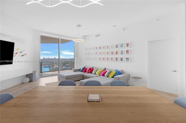 living room with light wood-type flooring, floor to ceiling windows, and visible vents