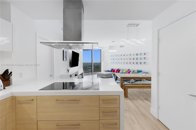 kitchen with open floor plan, light countertops, island exhaust hood, and black electric stovetop