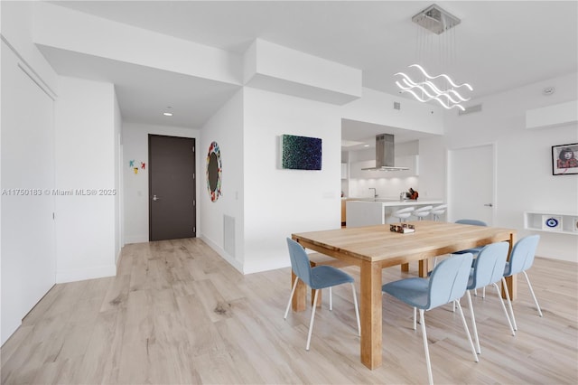 dining area with an inviting chandelier, light wood-style flooring, and baseboards