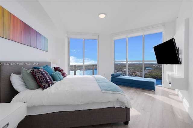 bedroom with light wood-type flooring, expansive windows, and access to exterior