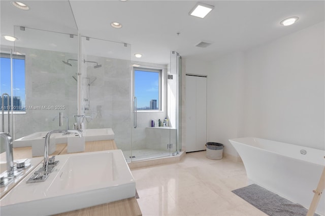 bathroom with a freestanding bath, double vanity, a sink, and a shower stall