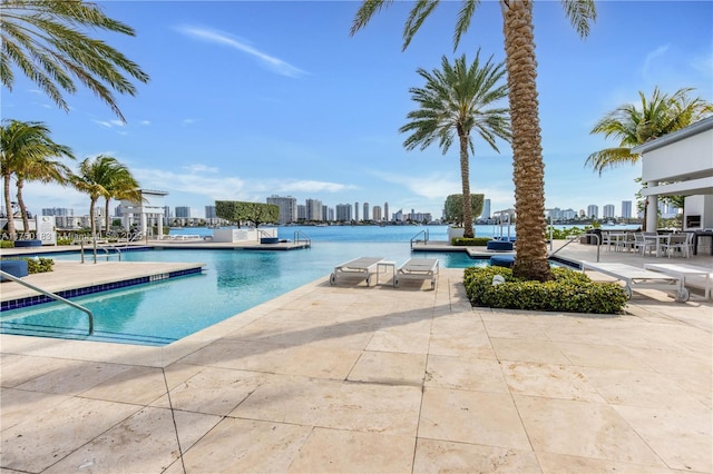 pool featuring a water view, a patio area, and a view of city