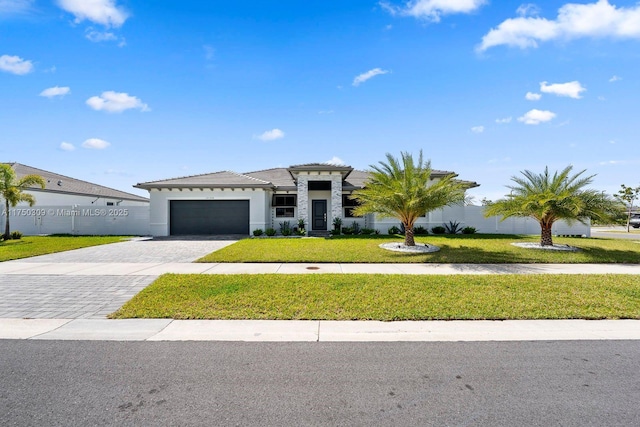 view of front facade featuring an attached garage, a tiled roof, decorative driveway, stucco siding, and a front yard