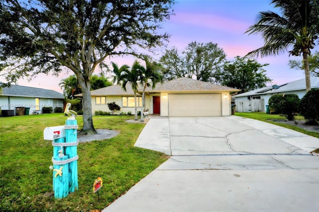 ranch-style house with a garage, concrete driveway, and a lawn