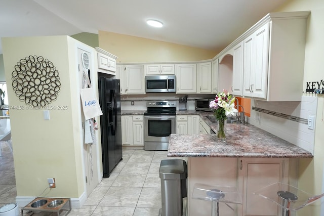 kitchen with stainless steel appliances, lofted ceiling, white cabinets, a sink, and a peninsula