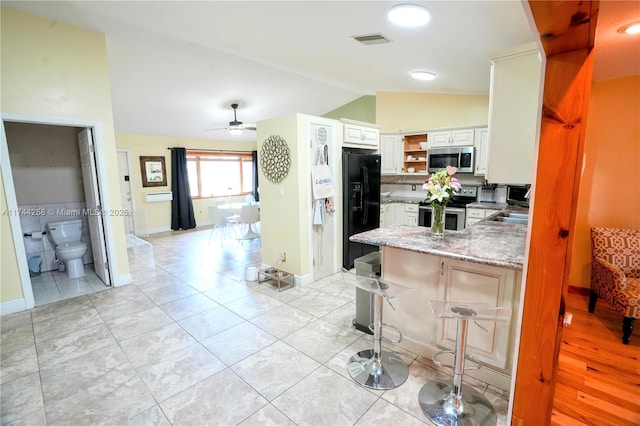 kitchen featuring white cabinets, a peninsula, stainless steel appliances, a kitchen bar, and open shelves