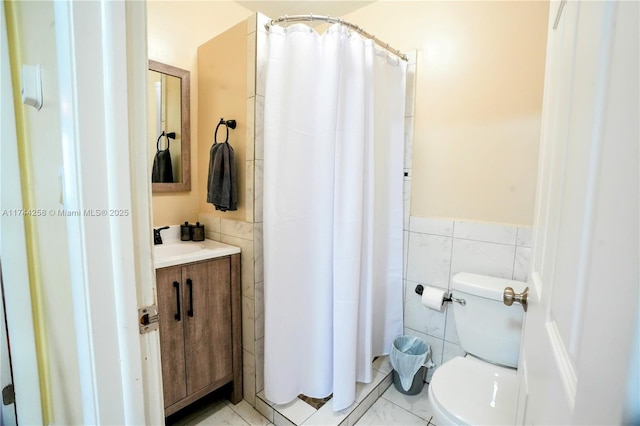 bathroom with a wainscoted wall, tile walls, toilet, vanity, and a shower with curtain