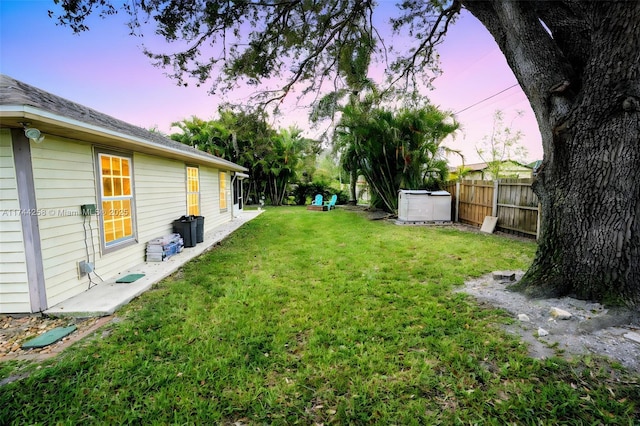 yard at dusk featuring fence, an outdoor structure, and a shed