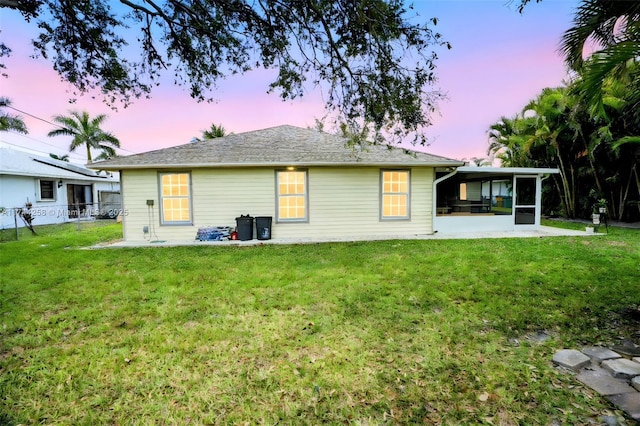 back of property featuring a sunroom, a patio area, a lawn, and fence