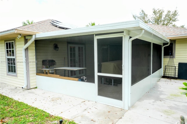 view of property exterior with a shingled roof and a sunroom