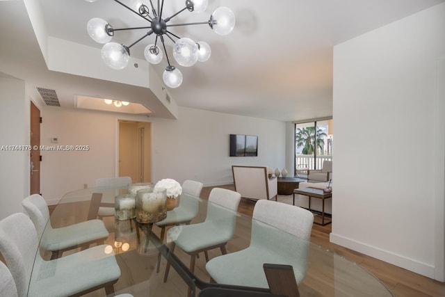 dining room featuring a notable chandelier, wood finished floors, visible vents, and baseboards