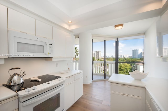 kitchen featuring white appliances, a view of city, light countertops, a wall of windows, and white cabinetry