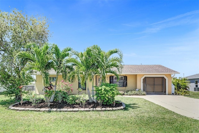 ranch-style home featuring a shingled roof, concrete driveway, an attached garage, a front yard, and stucco siding