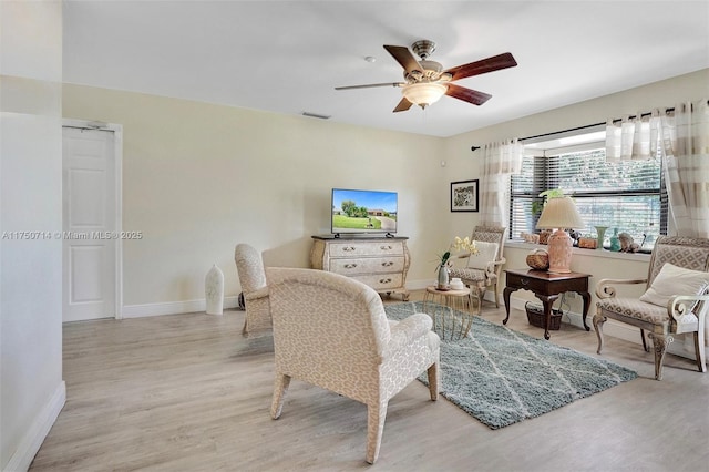 living room with ceiling fan, light wood finished floors, visible vents, and baseboards