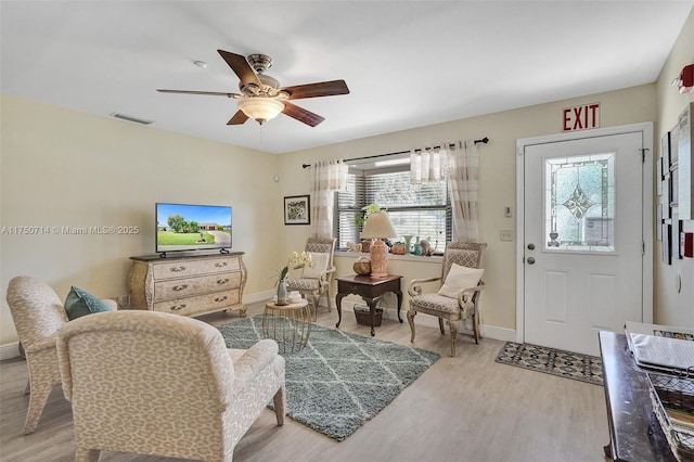 interior space featuring a ceiling fan, baseboards, visible vents, and wood finished floors