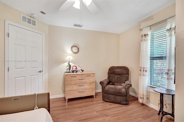 living area featuring baseboards, visible vents, ceiling fan, and light wood finished floors