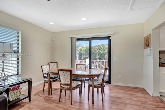 dining area with light wood-style floors, baseboards, and a textured ceiling