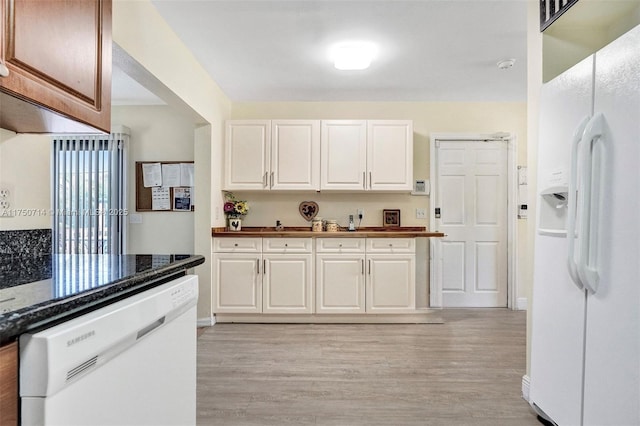 kitchen with white appliances, dark countertops, light wood-style floors, and white cabinets