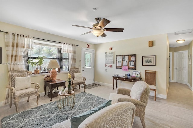 living area with a ceiling fan, light wood finished floors, and baseboards