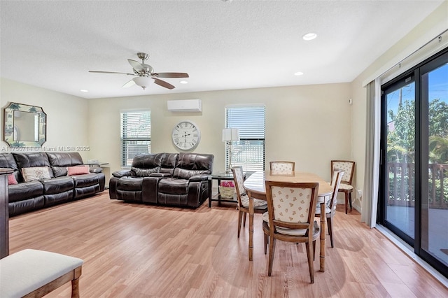 living area with a wall unit AC, light wood-style floors, a textured ceiling, and recessed lighting