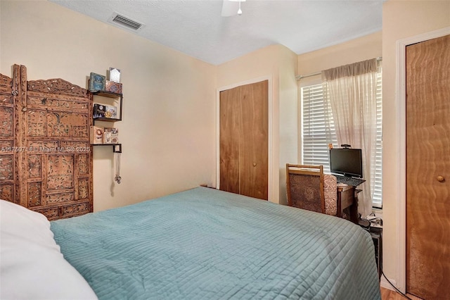 bedroom featuring ceiling fan, visible vents, and a textured ceiling