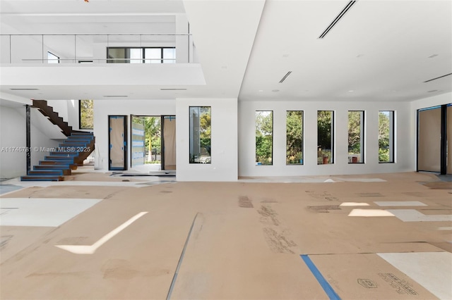 unfurnished living room featuring visible vents and stairs