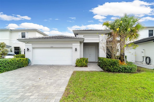 view of front of house featuring a front lawn, decorative driveway, an attached garage, and stucco siding