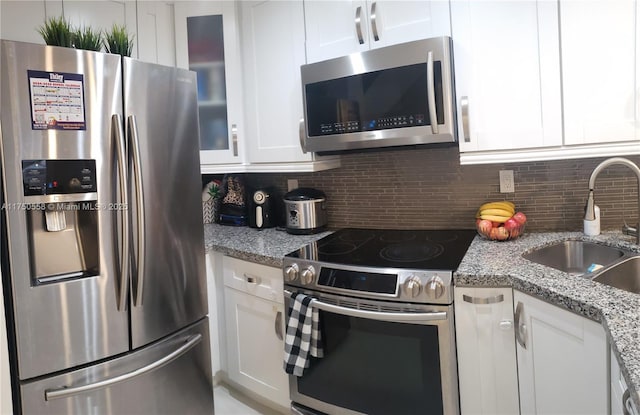 kitchen with stainless steel appliances, white cabinetry, a sink, and tasteful backsplash