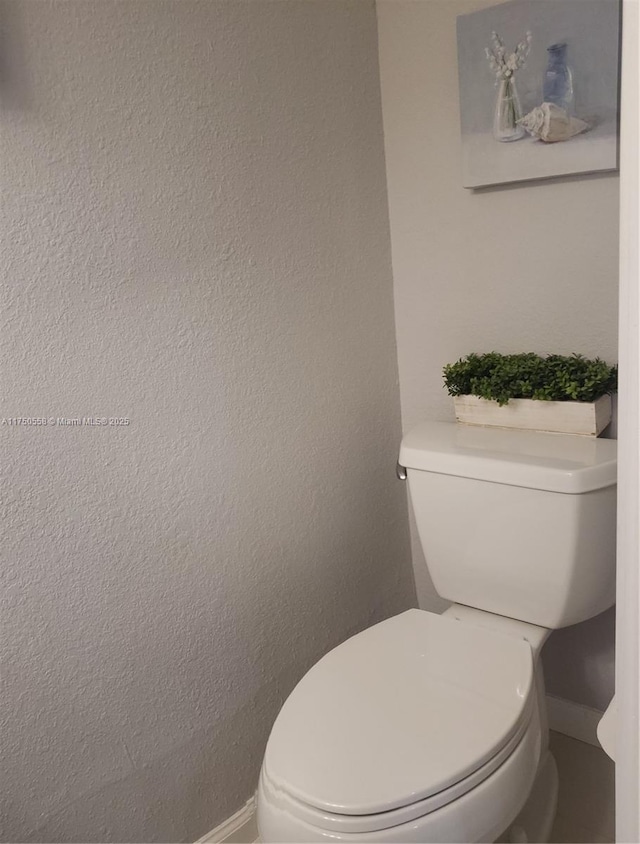 bathroom featuring a textured wall and toilet