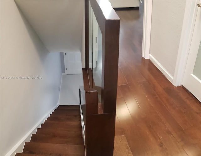 staircase featuring baseboards and wood finished floors