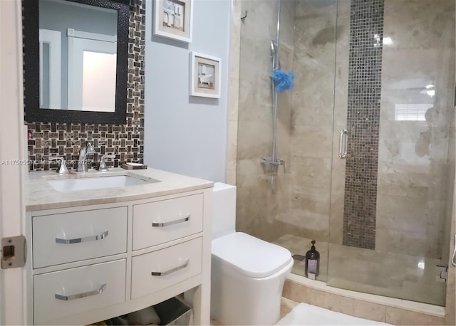 bathroom featuring toilet, a stall shower, backsplash, and vanity