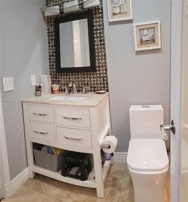 bathroom featuring baseboards, toilet, vanity, and decorative backsplash