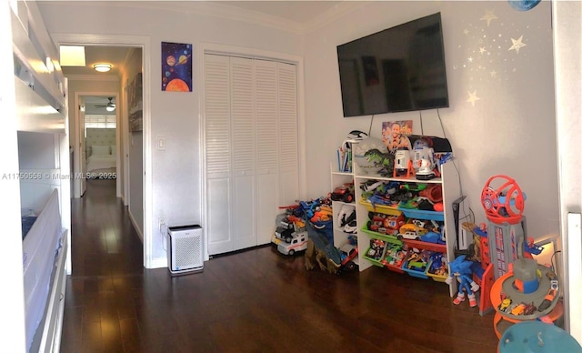 playroom with a ceiling fan, crown molding, and wood finished floors