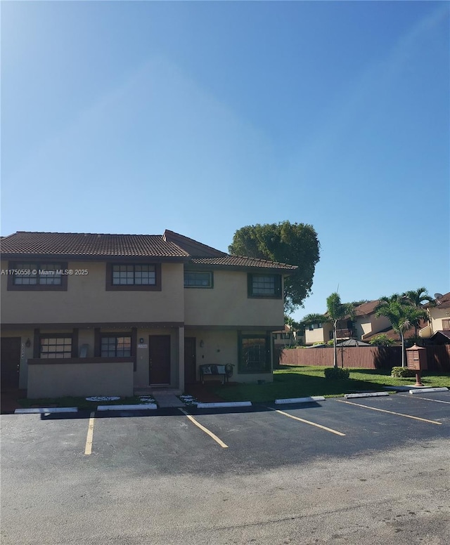 exterior space with uncovered parking, fence, and stucco siding