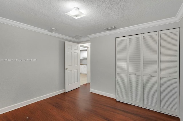 unfurnished bedroom with dark wood-style floors, a closet, baseboards, and crown molding