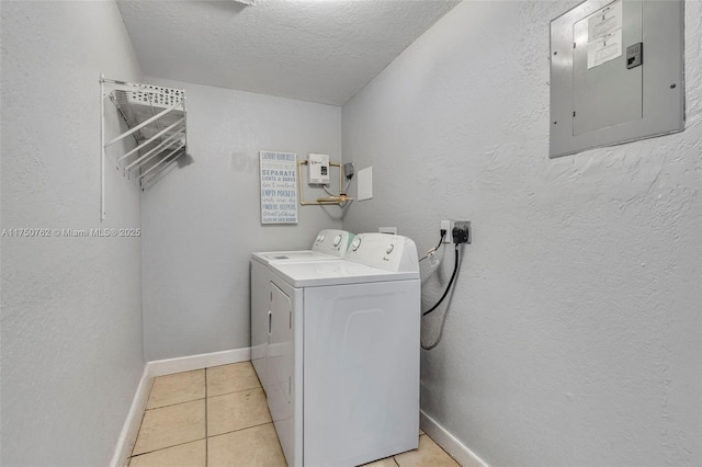 clothes washing area with light tile patterned floors, washer and dryer, laundry area, electric panel, and baseboards