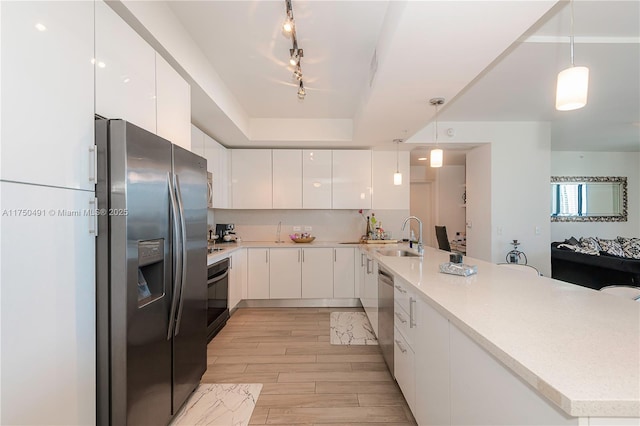 kitchen with light countertops, appliances with stainless steel finishes, decorative light fixtures, and white cabinetry