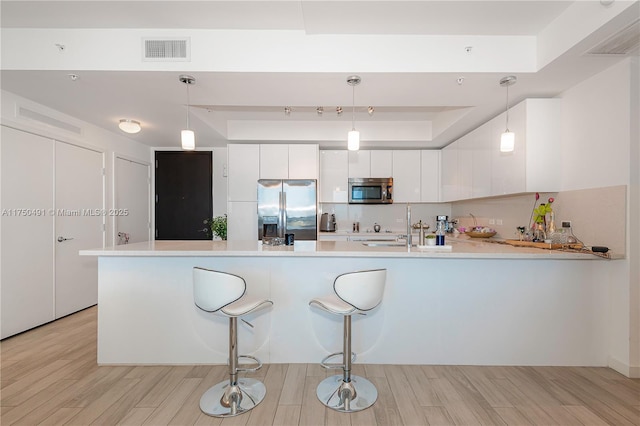 kitchen featuring stainless steel appliances, pendant lighting, light countertops, and visible vents
