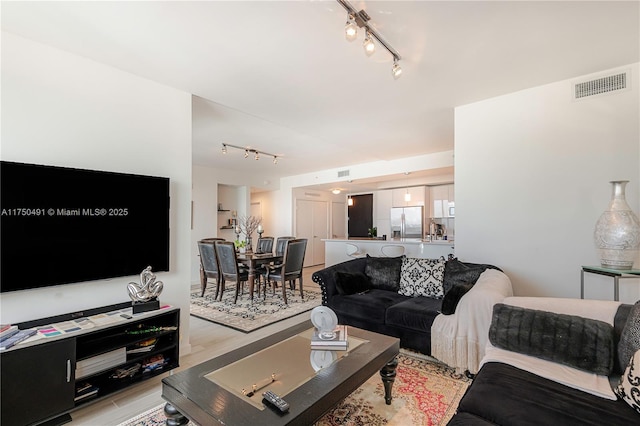 living room featuring light wood finished floors, visible vents, and track lighting