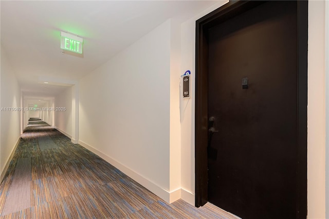 corridor with dark wood-style flooring and baseboards