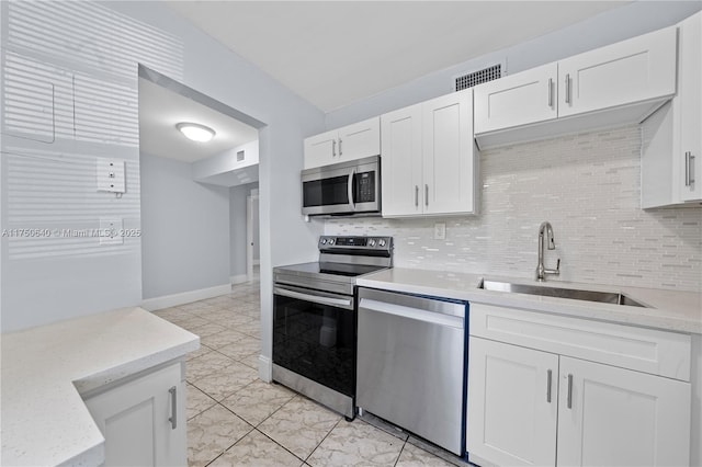 kitchen featuring appliances with stainless steel finishes, white cabinets, a sink, and decorative backsplash