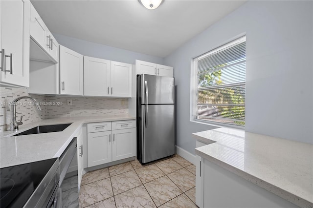 kitchen featuring appliances with stainless steel finishes, white cabinetry, a sink, and tasteful backsplash