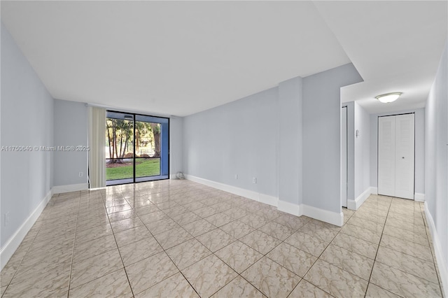 spare room with expansive windows and baseboards