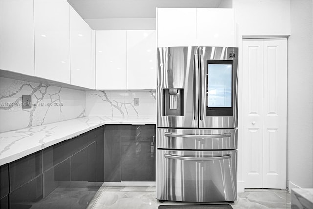 kitchen with light stone counters, marble finish floor, stainless steel refrigerator with ice dispenser, white cabinets, and modern cabinets